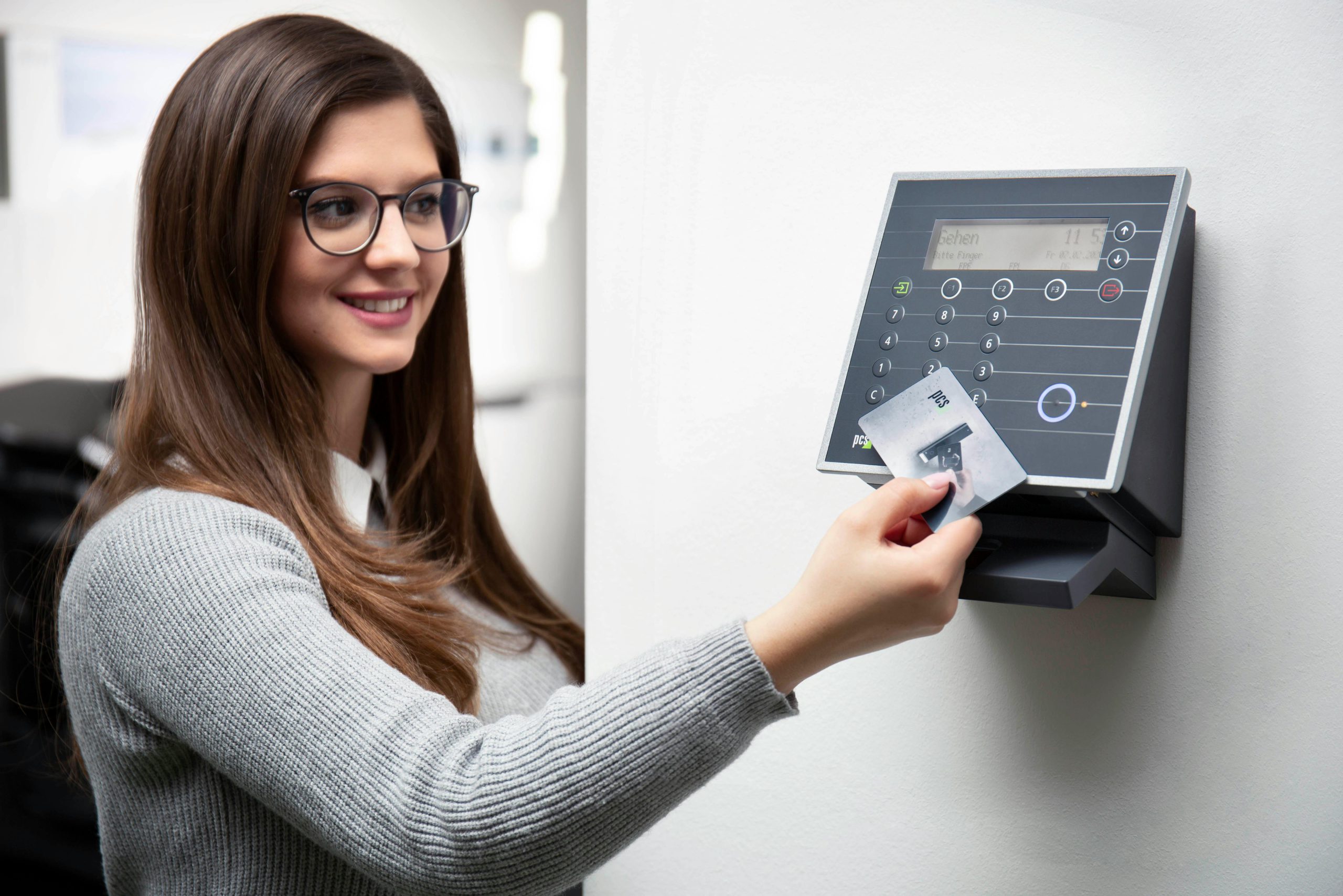 Smiling woman uses a card reader for secure office access in Munich.